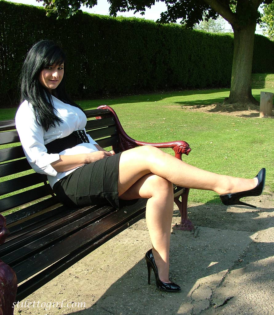 Dark haired female displays some leg and her stiletto heels on a park bench порно фото #426400529