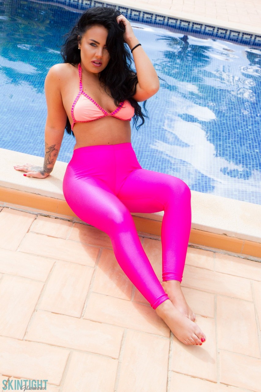 Glamour model Olivia Paige slips pink leggings over bikini bottoms by a pool porn photo #427600397