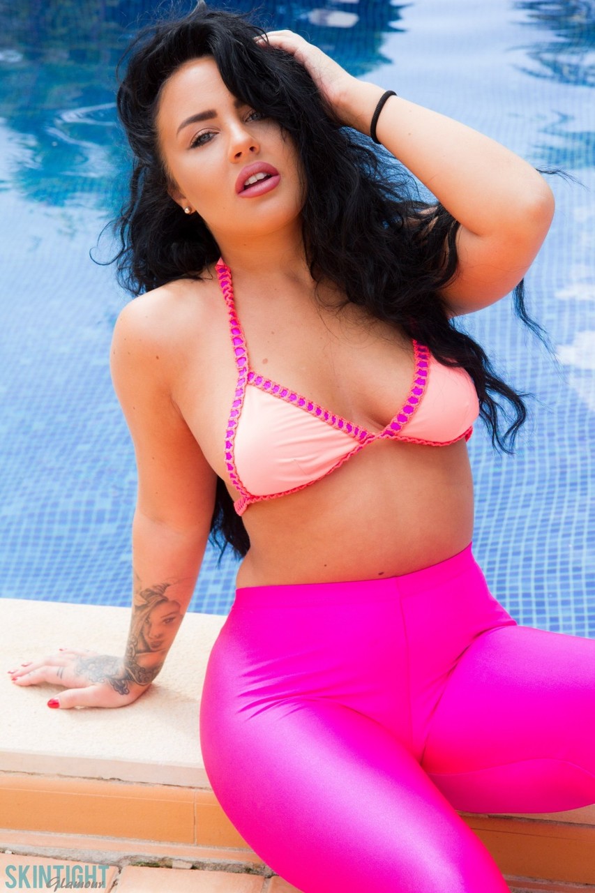 Glamour model Olivia Paige slips pink leggings over bikini bottoms by a pool foto pornográfica #427600401