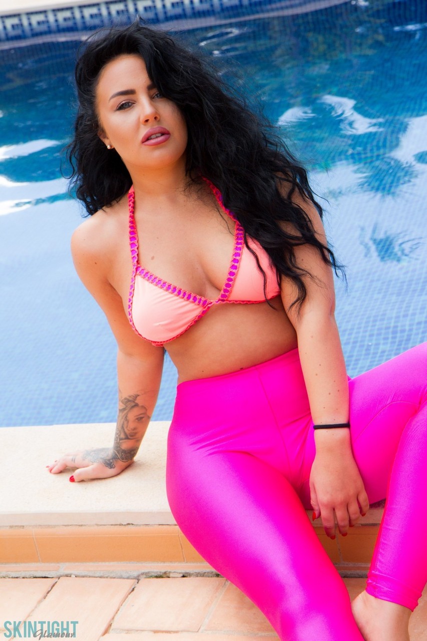 Glamour model Olivia Paige slips pink leggings over bikini bottoms by a pool foto pornográfica #427600409