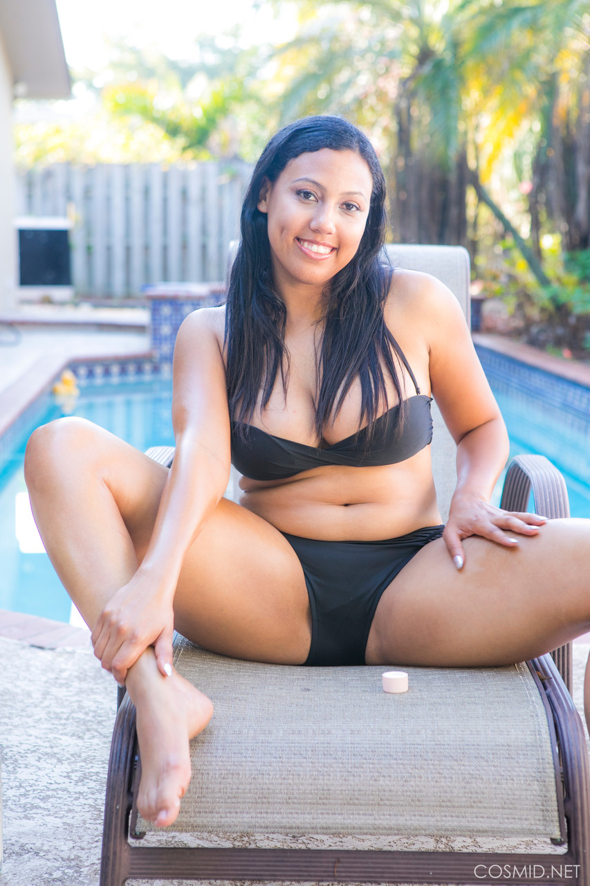 Mollige zwarte amateur verwijdert haar bikini om naakt te poseren op stoel bij een zwembad