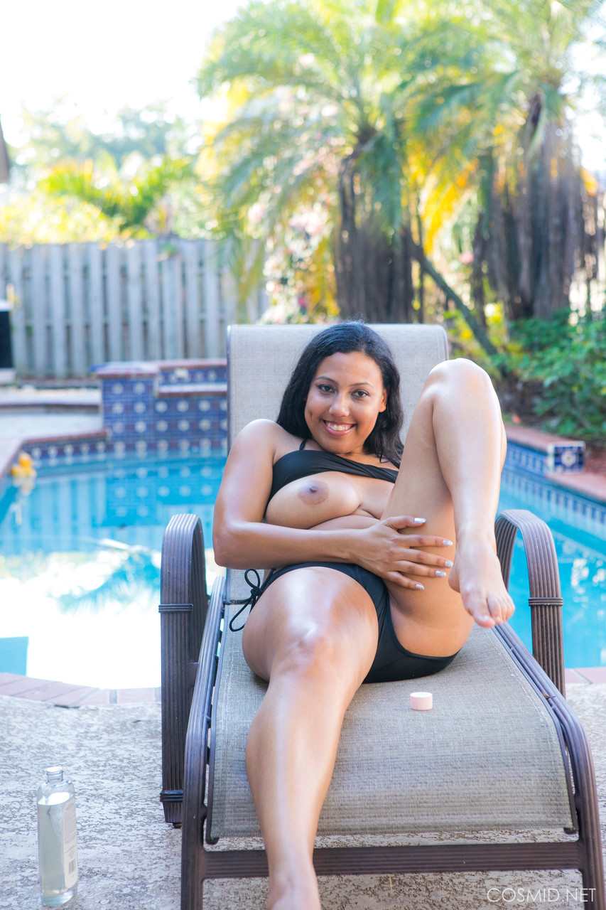 Chubby black amateur removes her bikini to pose nude on chair by a pool photo