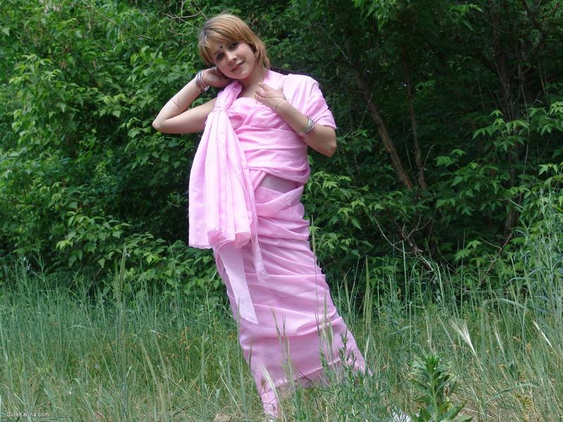 A young competitor named Liza is seen naked in a field located near the line of trees.