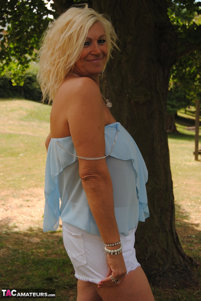 Hot mature Platinum Blonde spreading legs in shorts on blanket under the trees foto porno #425508011