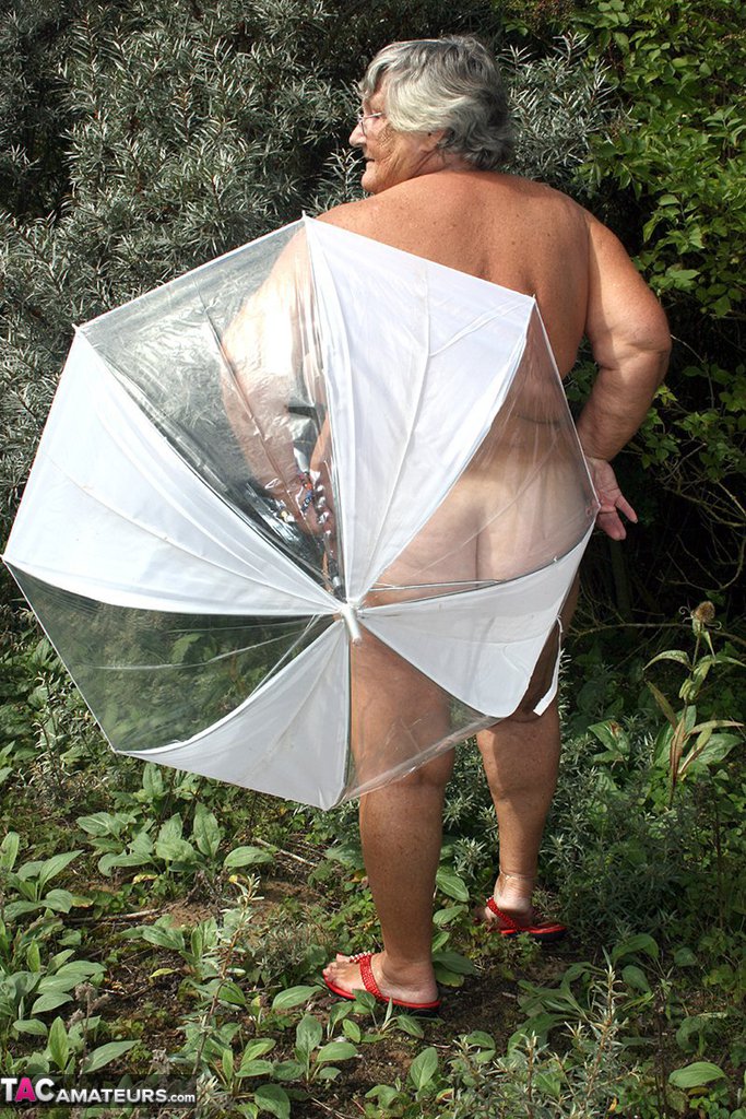 Obese oma Grandma Libby holds an umbrella while posing naked by fir trees 色情照片 #428473395