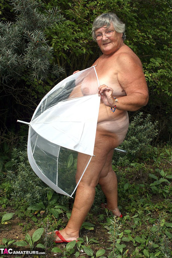 Obese oma Grandma Libby holds an umbrella while posing naked by fir trees ポルノ写真 #428543504