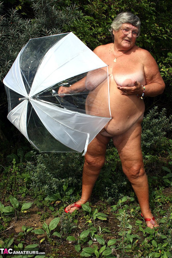 Obese oma Grandma Libby holds an umbrella while posing naked by fir trees zdjęcie porno #428543506