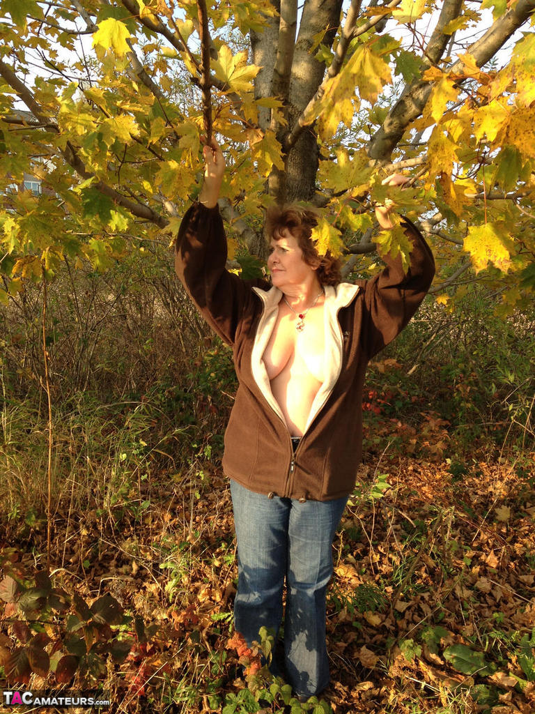 Under a tree, an older woman named Busty Bliss displays her big natural breasts.