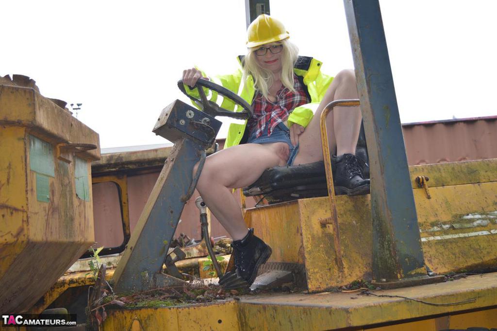 In an outdoor activity, Barby Slut bares herself on heavy equipment at a job site.