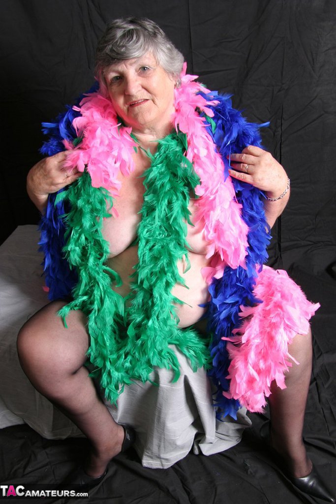 Grandma Libby, the fat amateur from Britain displays her big tits while wearing feather boas.