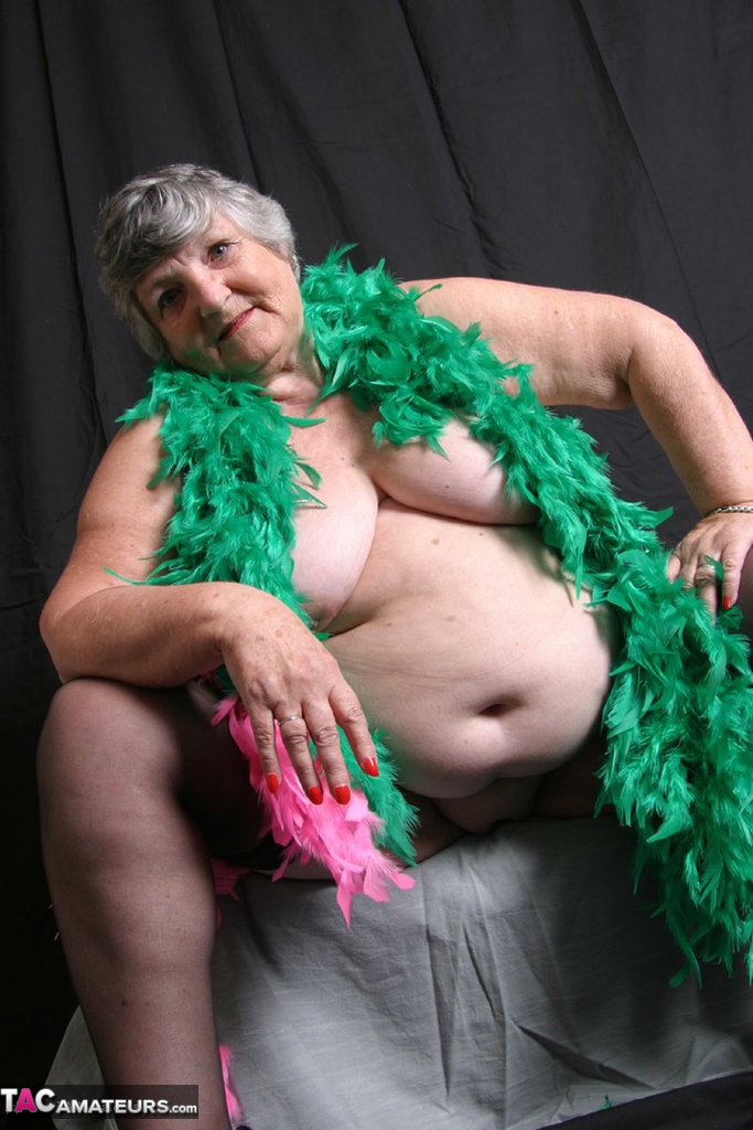 Despite her body being fat and not well-fitted, Grandma Libby from the UK displays her big tits while wearing feather boas.