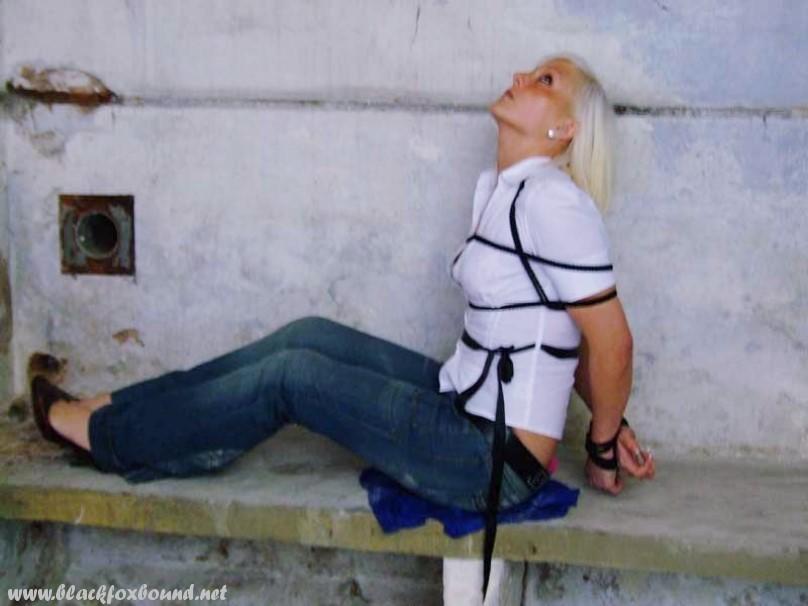 In blue jeans and a white shirt, a British woman is tied up and gagged.