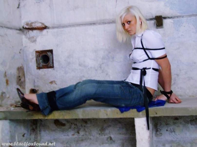 An American woman in blue jeans and white shirt is tied up and gagged.