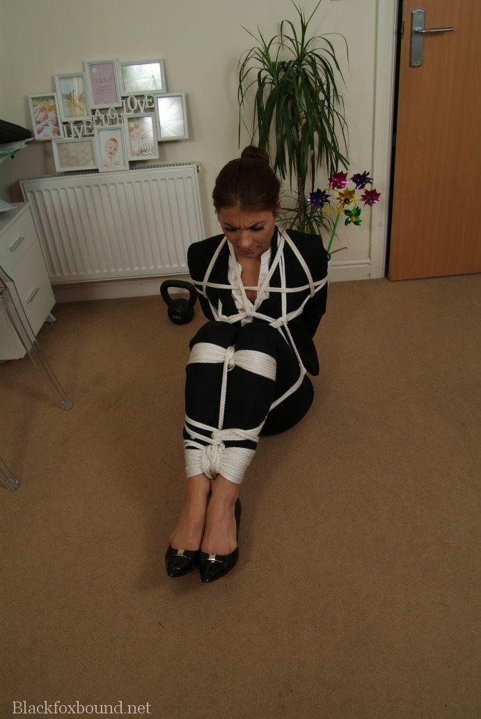 A fully clothed woman is held in place after being tied up with rope.