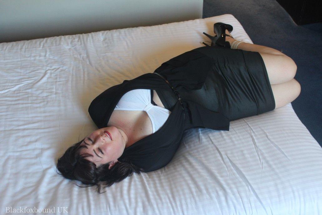 The brunette lady displays her breasts on a bed, bound and gagged.