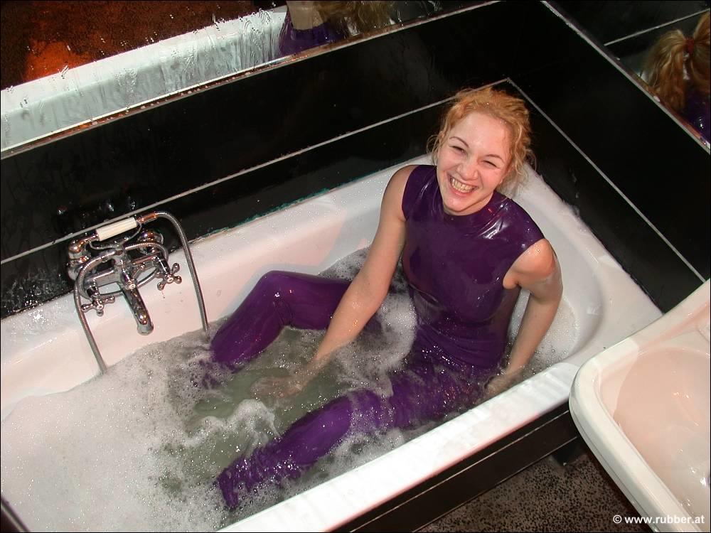 The white girl exposes her bare feet while bathing in purple latex clothing.