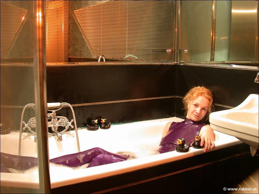 The naked feet of a white girl are observed while she takes a bath in purple latex clothing.