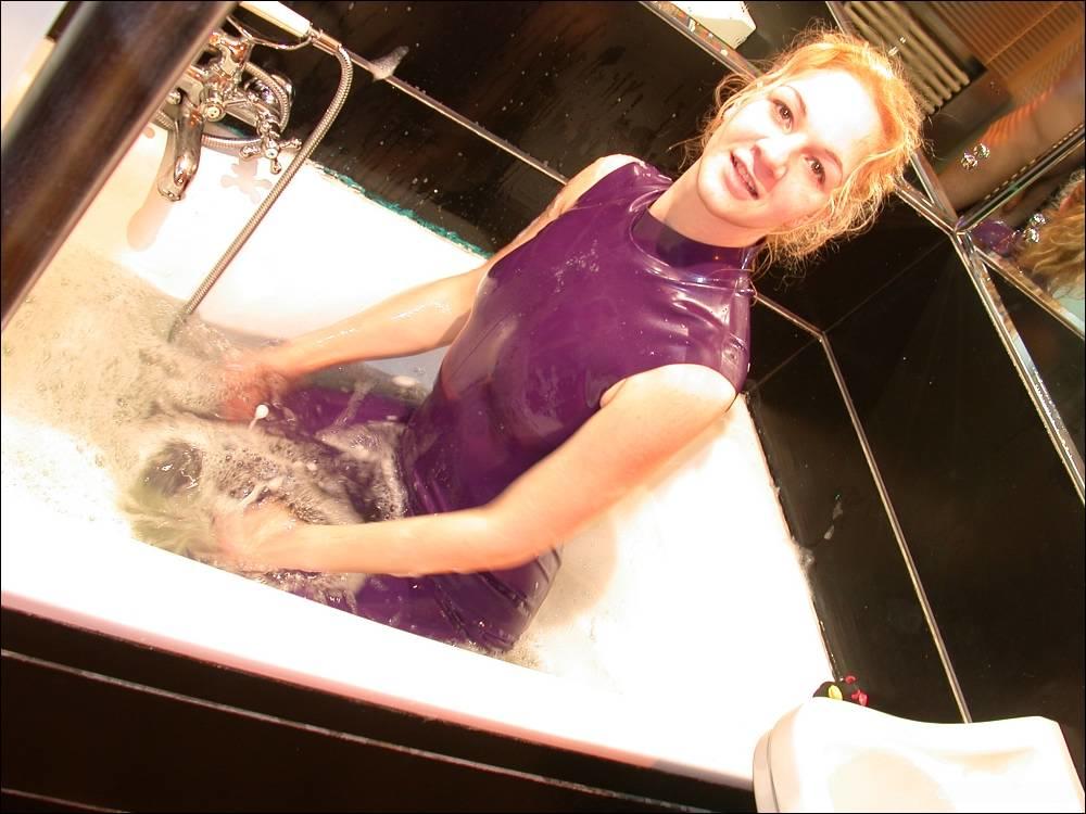 A white girl bares her feet while bathing in purple latex clothing.