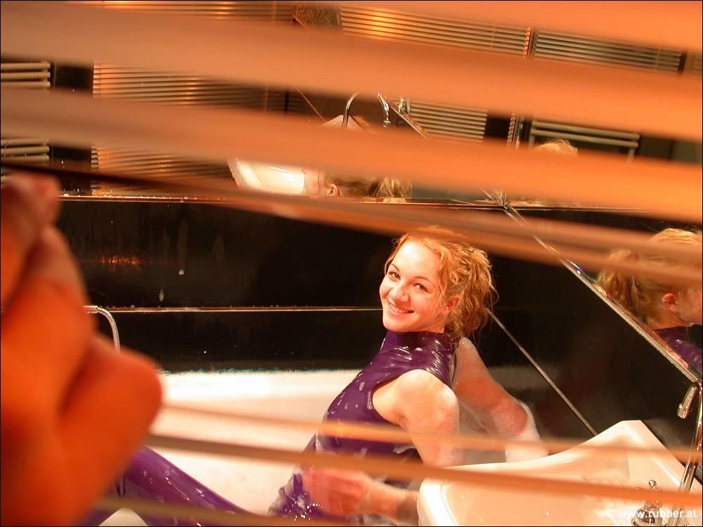The white girl exposes her bare feet while bathing in purple latex clothing.