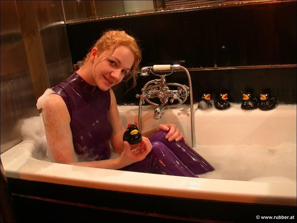 The naked feet of a white girl are observed while she takes a bath in purple latex clothing.