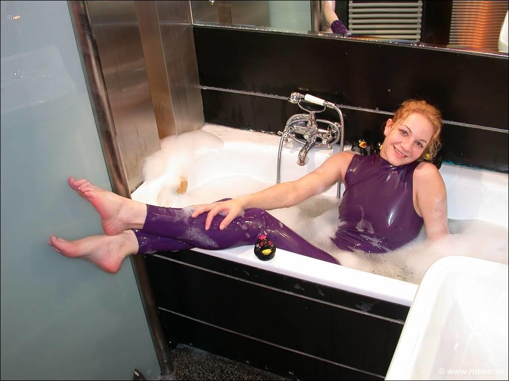 White girl wears purple latex and she shows her bare feet in the bath.