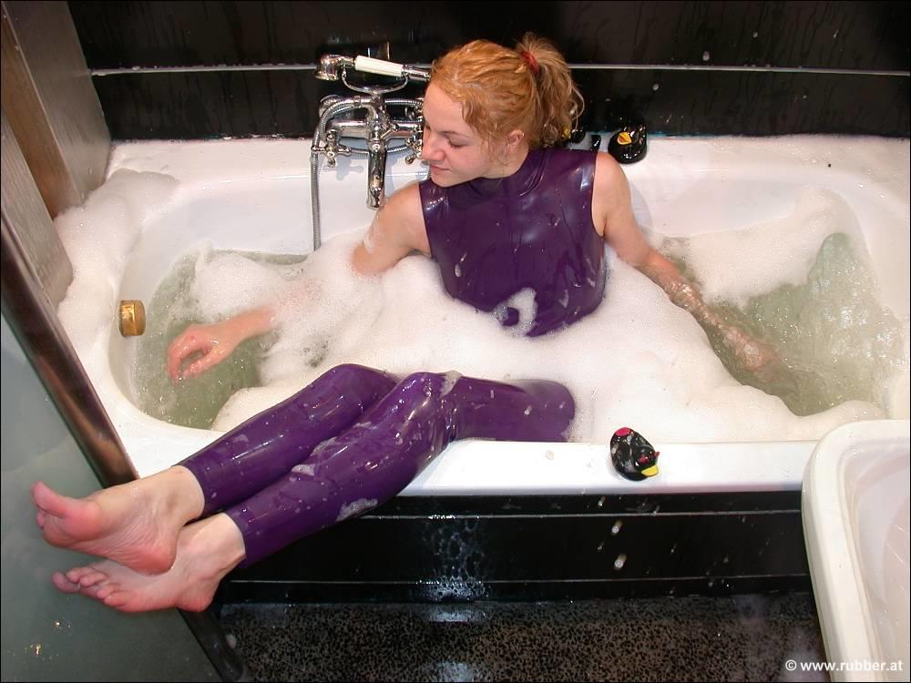 A white girl bares her feet while bathing in purple latex clothing.
