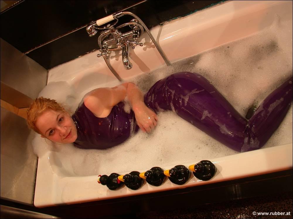 The white girl exposes her bare feet while bathing in purple latex clothing.