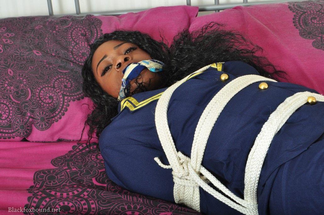 An Ebony stewardess finds herself in her uniform tied up and gagged on a bed.