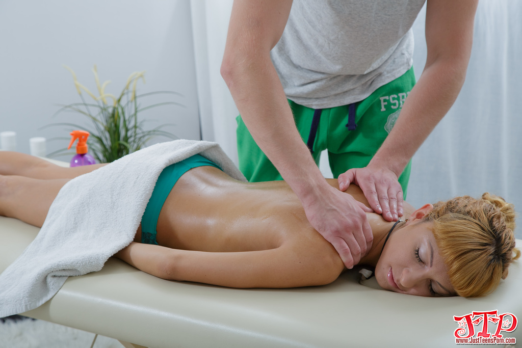 Young redhead receives massage from her massage attendant during a rub down.