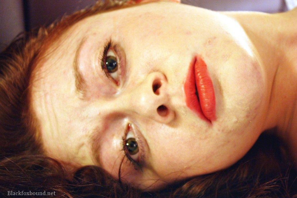 A natural redhead is seen cleaving while being restrained in her clothes on a bed.