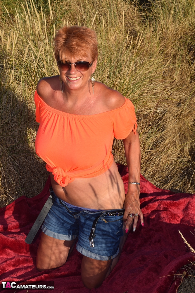 A fit and elderly woman named Dimonty exposes large natural phenomena on a blanket that overlooks the ocean.
