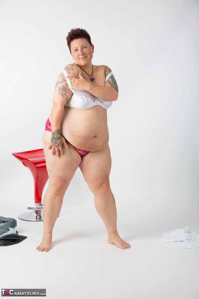 Tattoo girl, who is an elderly and unwell tattoo artist, gets completely naked and sits on a stool.