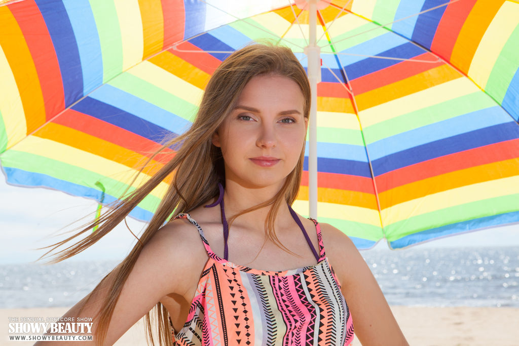 Beautiful young girl Dominika gets totally naked under an umbrella on a beach