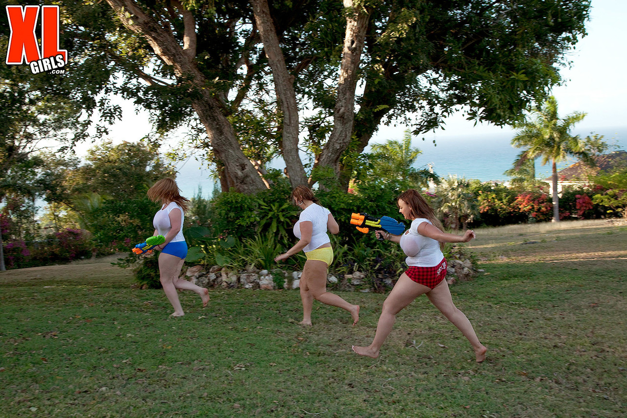 White t-shirts of girls with big t-shirts are soaked in water guns that are super-soaking and secured.