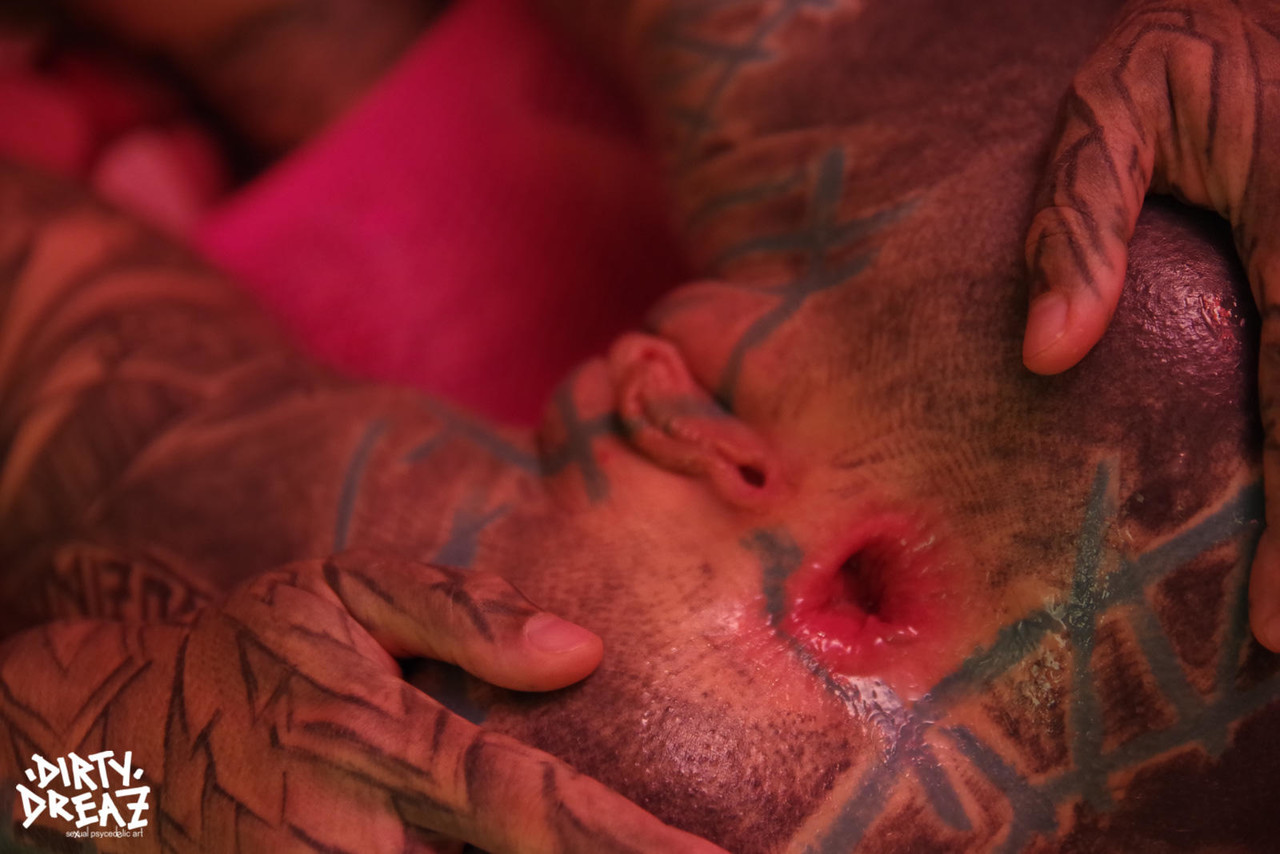 A heavily tattooed female extends her groin by stretching out with fingers.