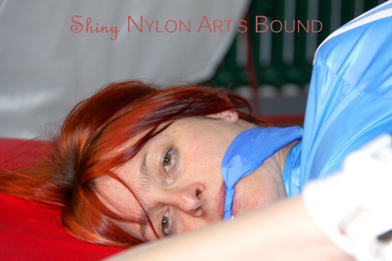 Sonja, wearing a lightblue shiny nylon, tied and gagged on the bed with ropes.