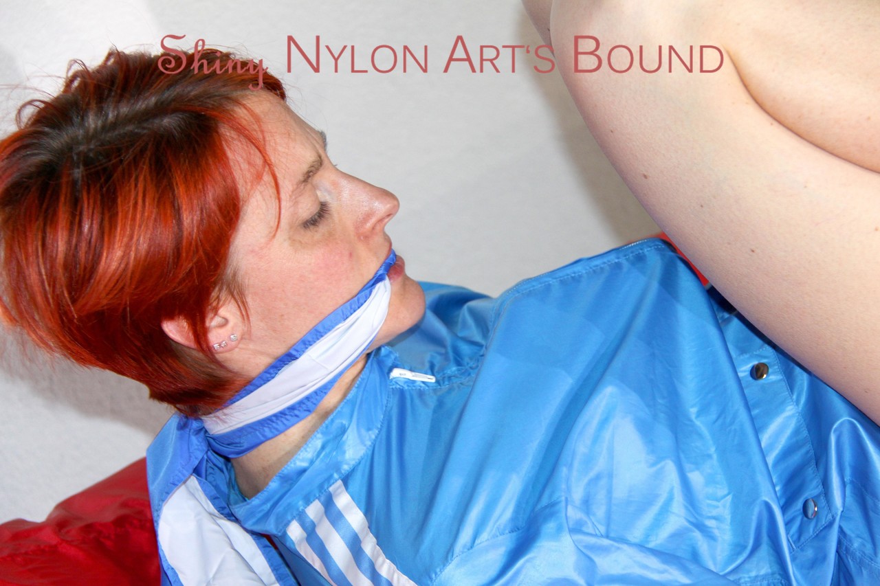 In a lightblue shiny nylon, Sonja was restrained and gagged on a bed with ropes.