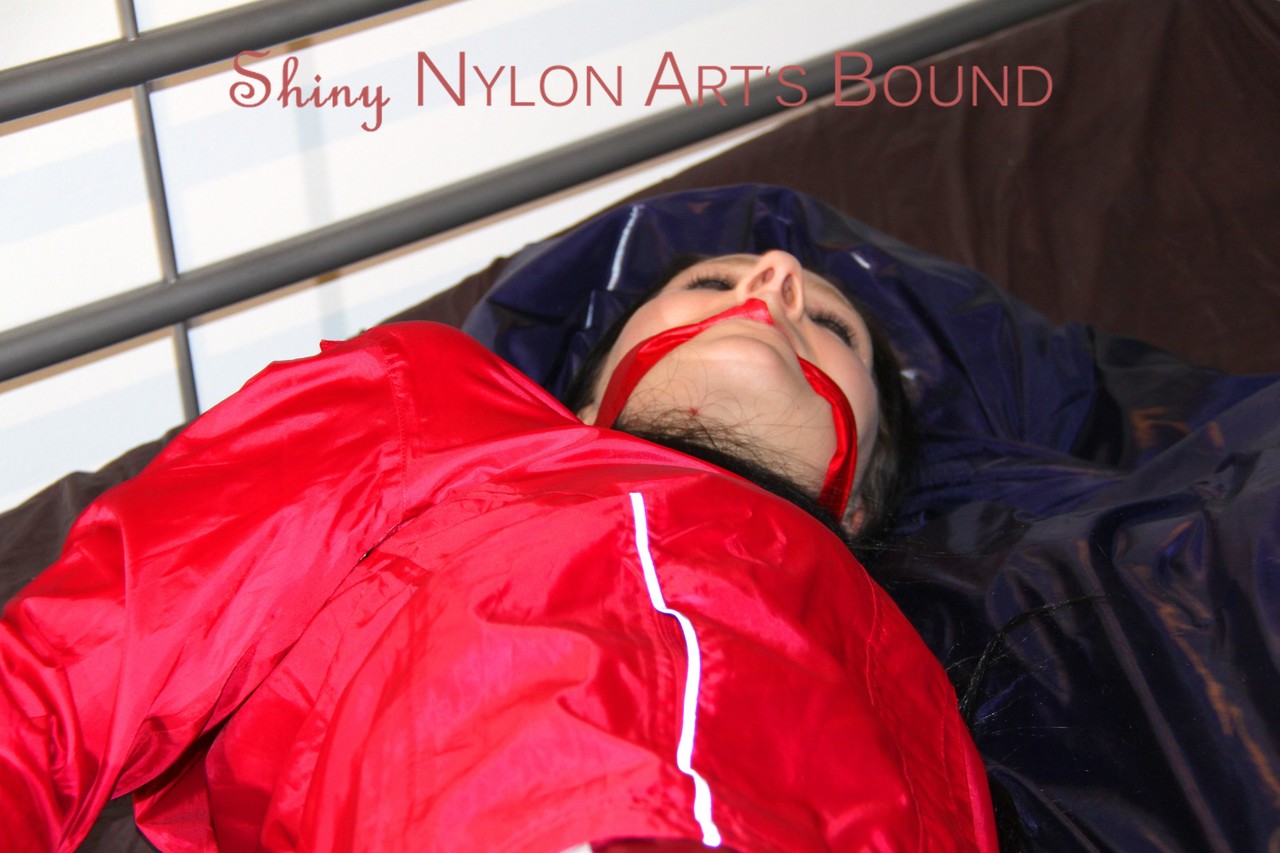 In seductive red shiny nylon shorts and a red bathing suit, Lucy was tied and gagged on the bed.