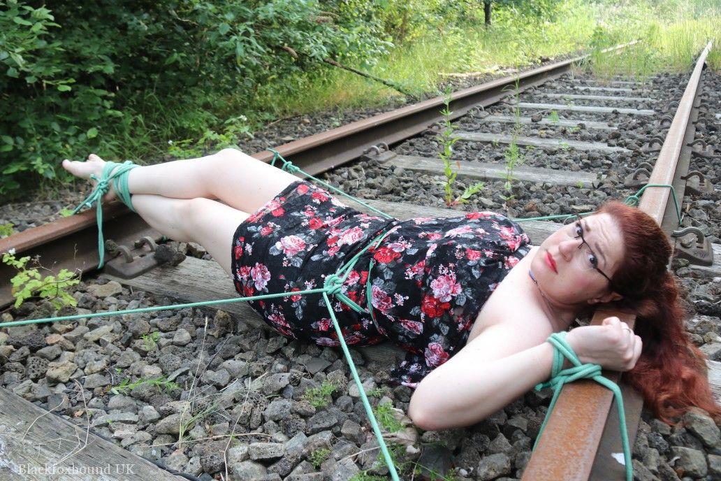 Dressed in glasses, the natural redhead is tied to train tracks.