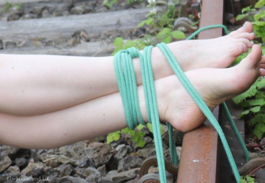 Dressed in clothing and glasses, a natural redhead is tied to train tracks.