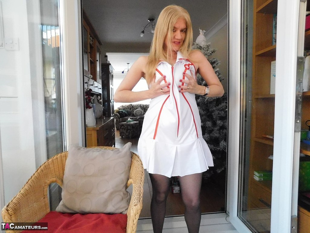 Older British nurse Lily May unzips her uniform on a wicker chair porn photo #422890208