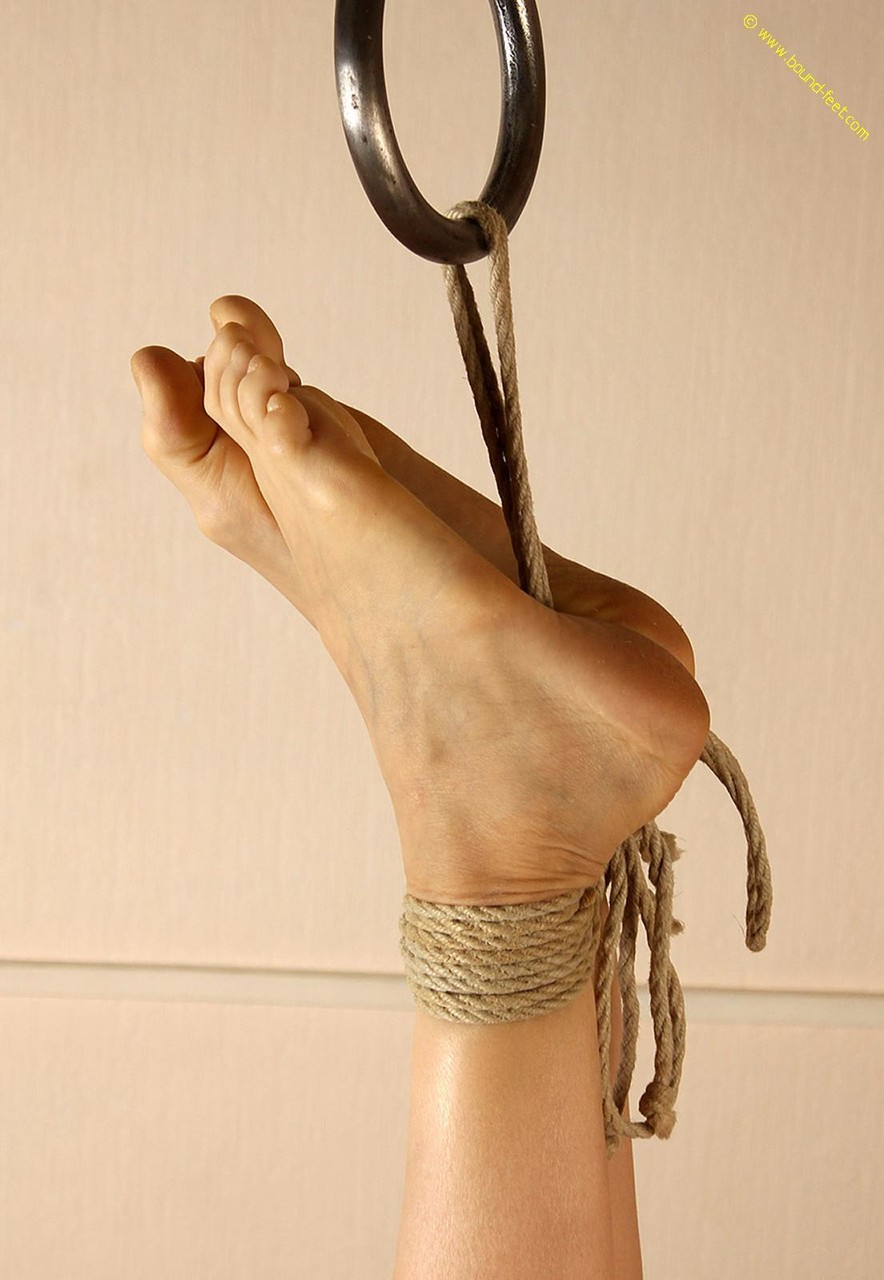 The bare feet of the naked woman are tied up by ropes around her ankles.