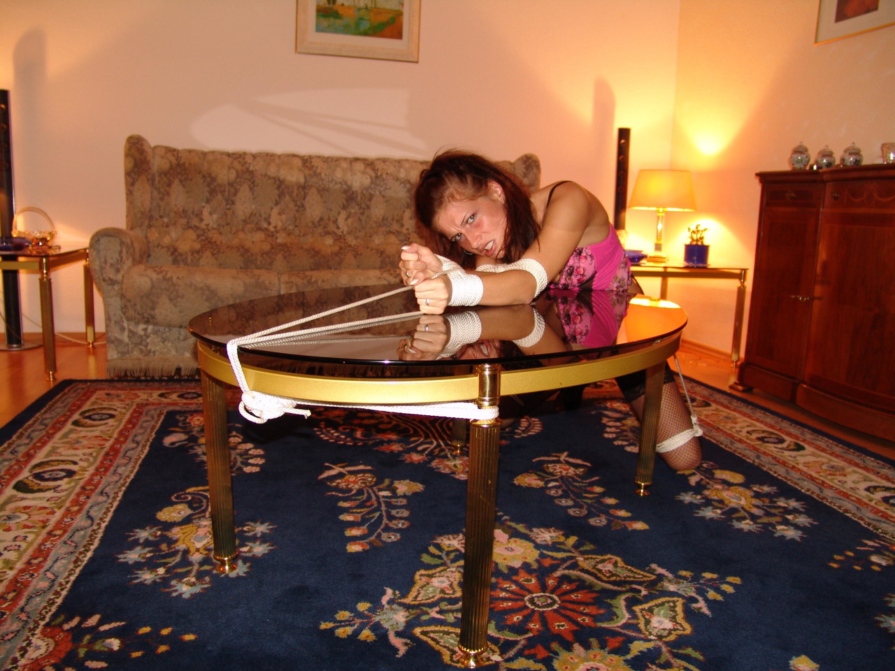 Rope tied over a coffee table: A white girl wears the ‘cleave gag’.