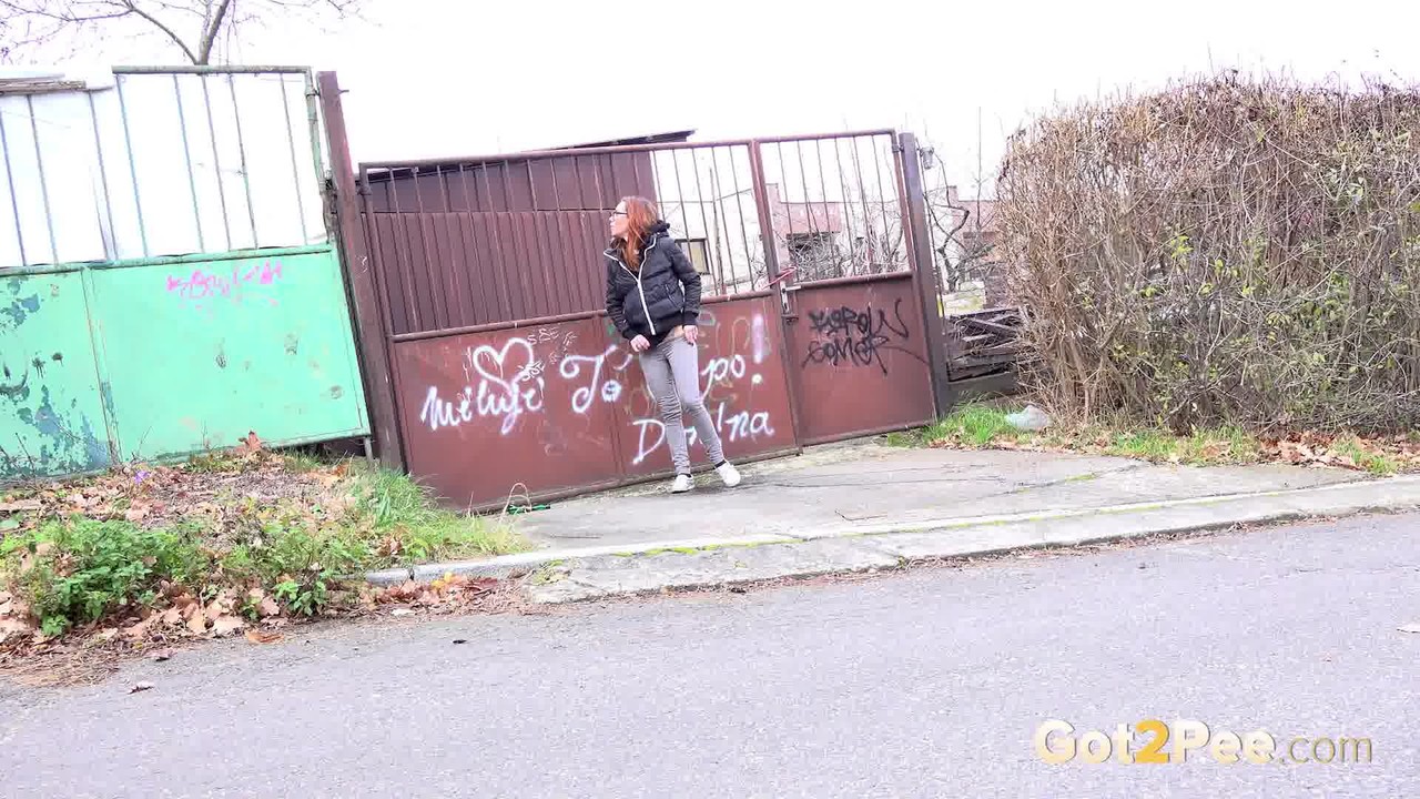 Redheaded girl pulls down her pants to take a piss in front of steel gates porn photo #426314429