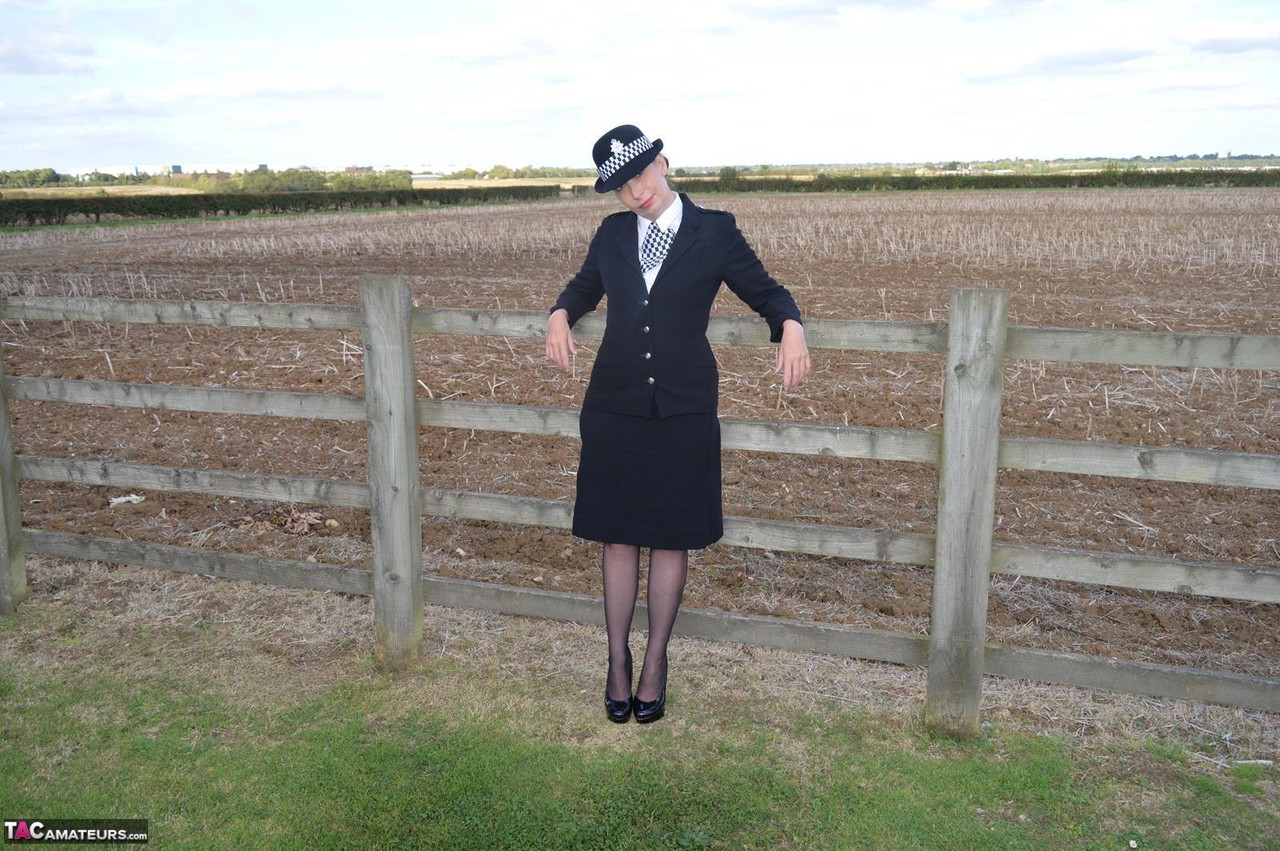 Mature policewoman Barby Slut removes her uniform against a fence at a farm porn photo #423264840