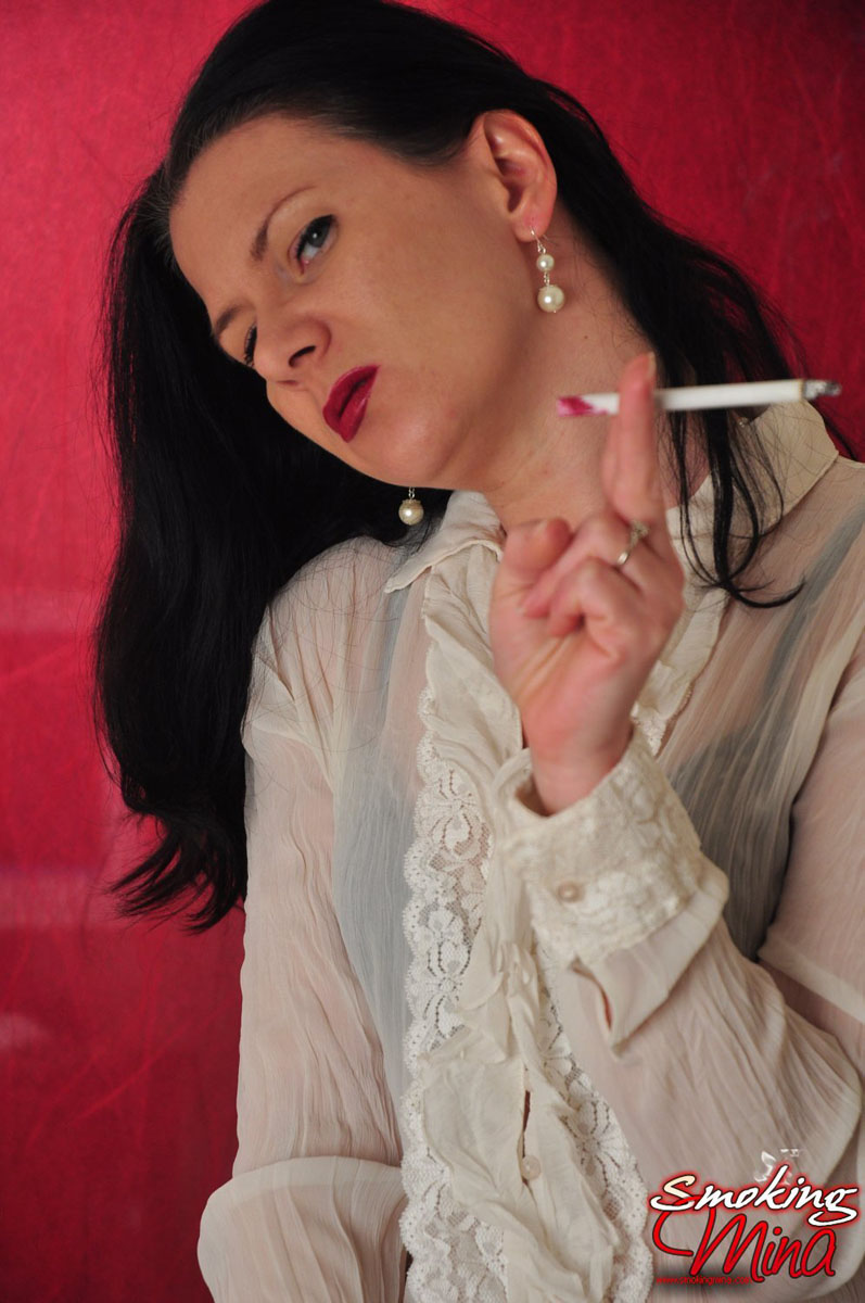 Brunette chick wears a sheer blouse while enjoying a smoke porn photo #428683883