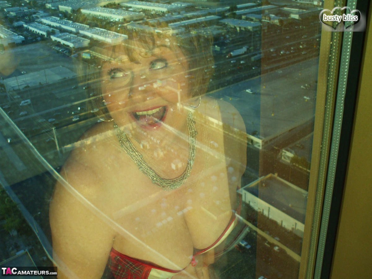 Mature woman Busty Bliss looses her big tits from a corset by her condo window porn photo #428649289
