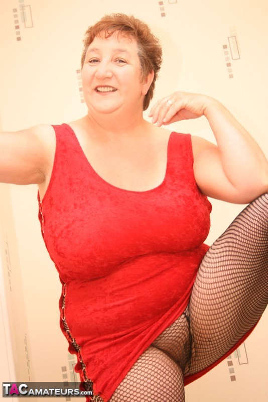 The older BBW Kinky Carol has short red hair and is naked with her natural tits.