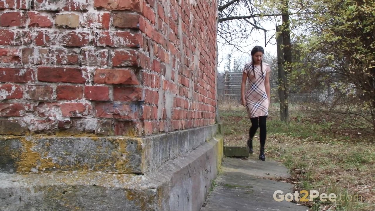 Nice girl pulls down black tights for quick pee behind a building porn photo #428762454