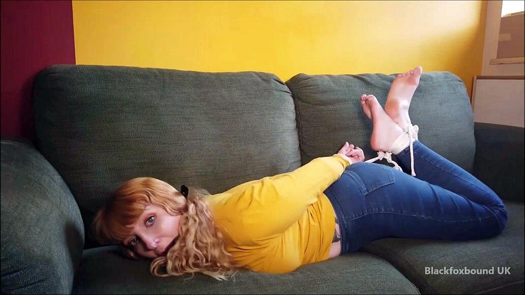 Barefoot white girl is hogtied on a sofa while ball gagged in her clothing foto porno #425132882